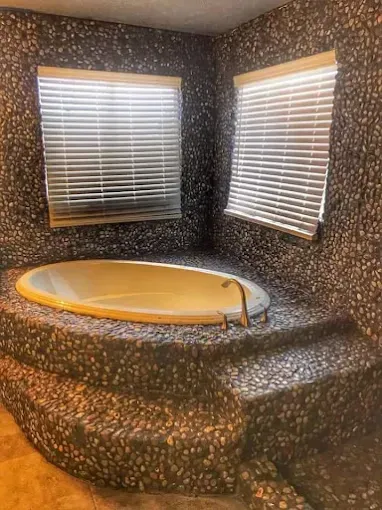 textured pebble bathtub surround in a spa-like bathroom remodel